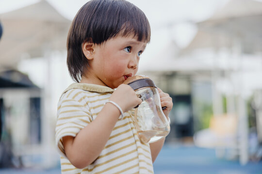Sweaty Child Drinking from Sippy Cup Outdoors