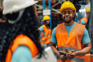 Warehouse worker holding scanner talking to female coworker