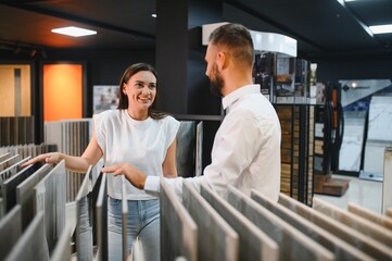 Young woman with sales man choosing tiles at building market
