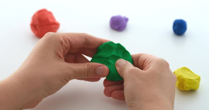 A woman squishing a ball of play clay. Close up.