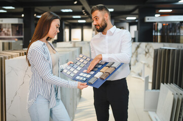 Woman choosing tiles in ceramic and furniture modern shop for her house