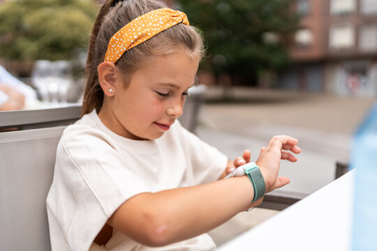 Young girl using smartwatch while sitting at table