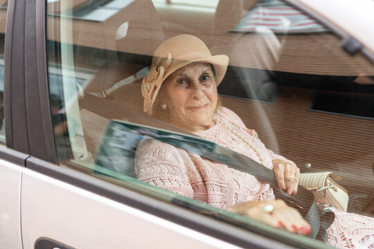 Elegant senior woman wearing a hat sitting in a car