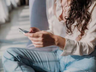 Beautiful Curly Haired Woman Relaxing at Home Using Smartphone