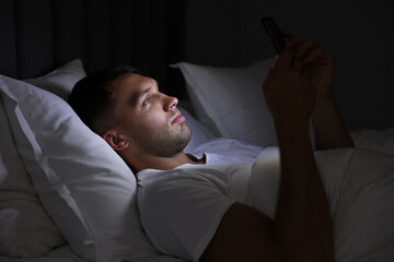 Bad habit. Man using smartphone in bed at night