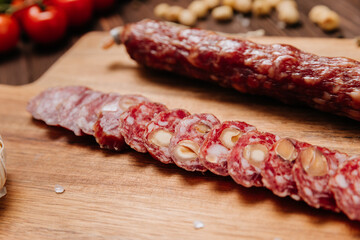 Sliced gourmet smoked salami on a wooden board with herbs, perfect for charcuterie boards and snacks