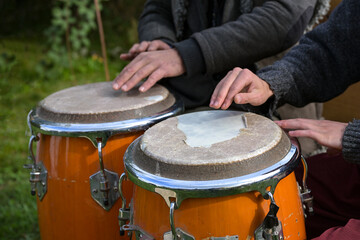 Obraz premium Two musicians playing conga with worn drumskin on an outdoor festival, musical instrument for Latin and Afro-Cuban music, salsa, jazz and more played as hand drums, selected focus