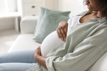 Fototapeta premium Pregnant woman on sofa at home, closeup