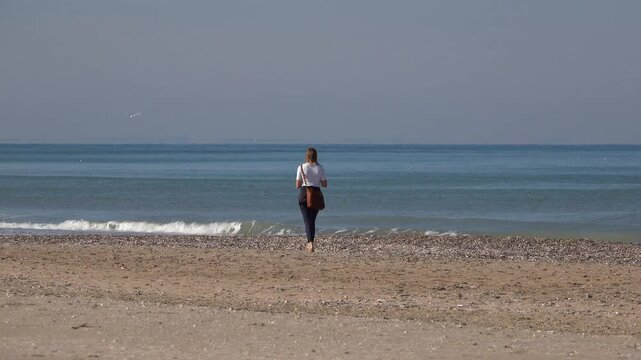 Une femme marche sur la plage au bord de la mer