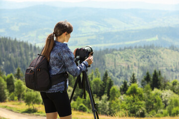 Photographer with backpack and camera on tripod taking picture of beautiful mountains. Space for...