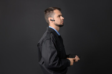Security guard in uniform with earpiece and gun on black background