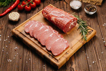 Fresh raw pork loin with rosemary on a wooden cutting board, perfect for cooking or grilling recipes