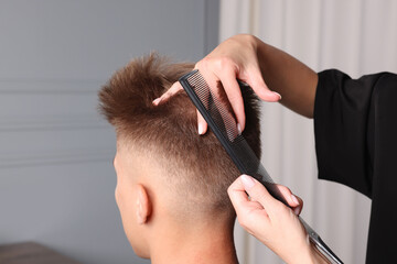 Professional barber making stylish haircut in salon, closeup