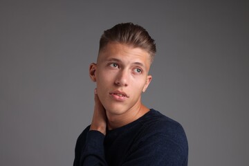 Handsome young man with stylish haircut on grey background