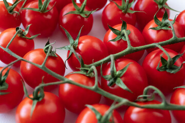 Bright red cherry tomatoes are neatly arranged on a light backdrop. Juicy vegetables of organic origin. A product suitable for vegan and vegetarian dishes. Background of vegetables.