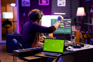 Sound engineer enhancing volume levels on daw software, editing soundtracks next to laptop showing...