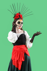 Beautiful woman dressed for Halloween showing something on green background