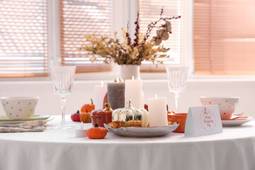Festive table setting with burning candles, pumpkins and greeting cards for Thanksgiving Day