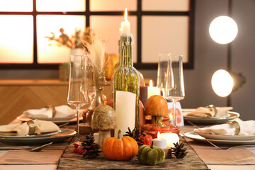 Beautiful table setting with burning candles, pumpkins and greeting cards for Thanksgiving dinner at evening