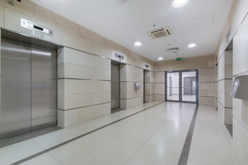 Spacious lobby in an office building. Modern elevators with metal doors. The room is .decorated...