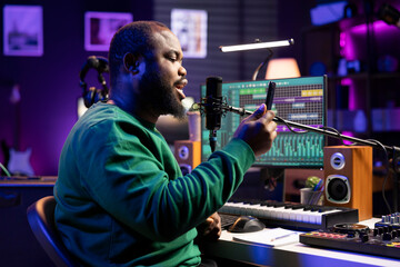 Young artist performer recording a new track written by him in home studio, using the verses from...