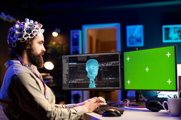 Software engineer with EEG headset starting mind upload on green screen PC, trying to gain bionic...