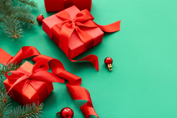 Red gift boxes with Christmas tree branches and balls on green background