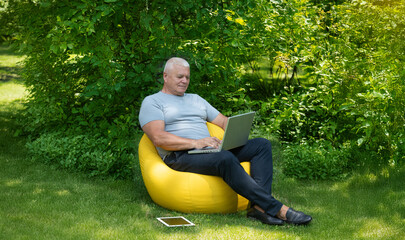 Obraz premium elderly adult man with laptop in garden