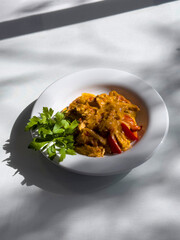 Traditional Turkish food, Turkish Cuisine. Chicken meat dish with cream, peppers and onions. A plate of food on a table with sunlight, with parsley on the side, top view