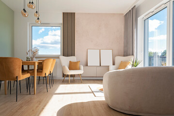 Modern living room with sofa, window and dining room with chair. Luxurious interior with wall with empty frame. Real estate.