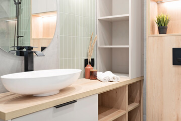 Luxury bathroom with mirror, stylish green tiles on the wall, ceramic washbasin on wooden cabinet. Modern interior of bathroom and bath.	