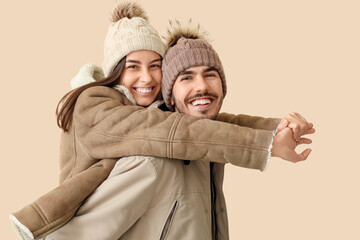 Loving couple in winter clothes hugging on beige background