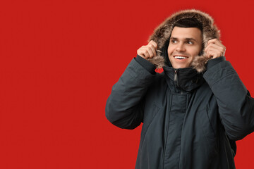 Young man in stylish puffer jacket on red background © Pixel-Shot