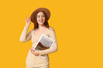 Stylish young girl with fashion magazine on yellow background