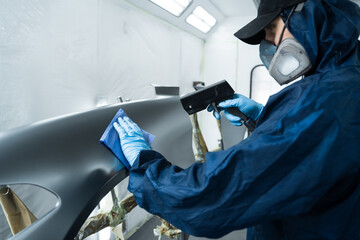 Using anti static gun to prevent damages and remove dust before covering car with paint. Mechanic is working with anti static gun to prepare metal for paintwork
