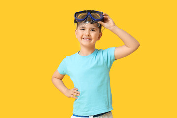 Cute little boy putting swimming mask off on yellow background