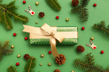 Christmas gift box with fir branches, balls and cones on green background