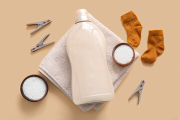 Laundry detergents with clothespins, towel and baby socks on beige background