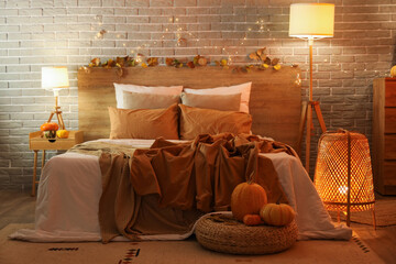 Interior of stylish bedroom with autumn decorations and candles in evening