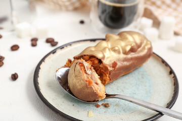 Plate with sweet eclair and coffee on light  background