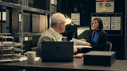 Senior detective asking his partner about legal documents in archive room, looking into crime...