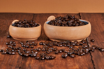 Close-up of freshly roasted coffee beans in a ceramic container on an old wooden table