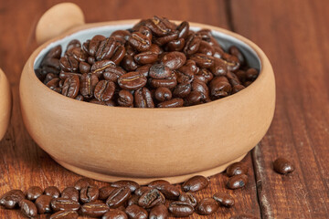 Close-up of freshly roasted coffee beans in a ceramic container on an old wooden table