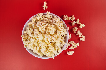 Striped cylindrical container with popcorn ready to enter the cinema, on a red background