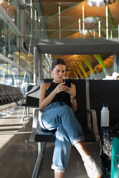 Traveler checks her itinerary on a smartphone sitting in an airport