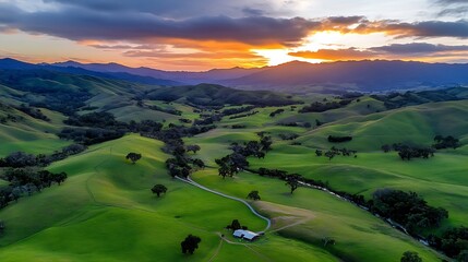 Fototapeta premium Aerial View of Rolling Green Hills and a Farm at Sunset