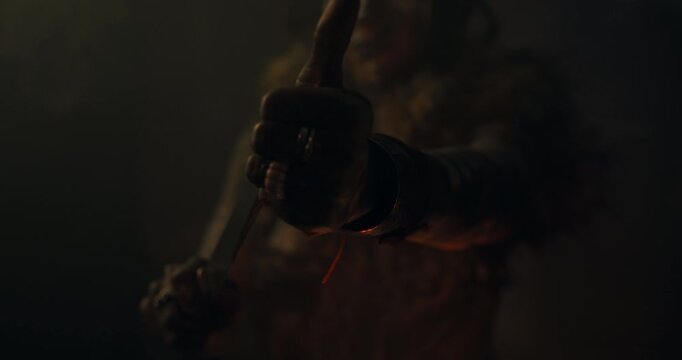 A witch in an old magical hut adds ingredients into the vase with burning embers to cast a curse