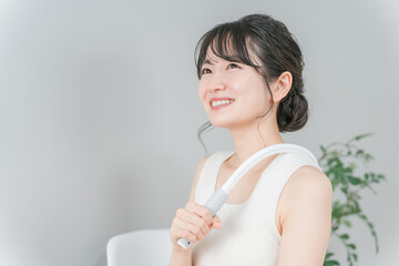 肩こりを健康グッズでマッサージするアジア人女性  © buritora