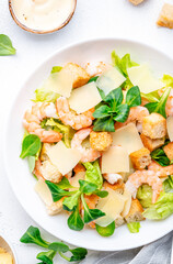 Foodie food Caesar salad with shrimp, iceberg and lumb lettuce, croutons, cheese and dressing. White background, top view