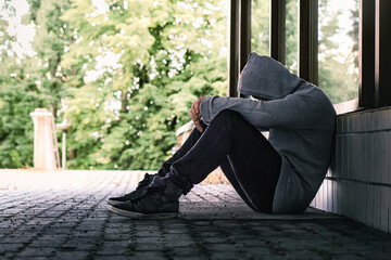 Trauma or guilt of a sad depressed man. Homeless outcast with drug addiction in city street. Loneliness, despair or discrimination. Shame of victim. Young poor lonely person suffer solitude or stress.